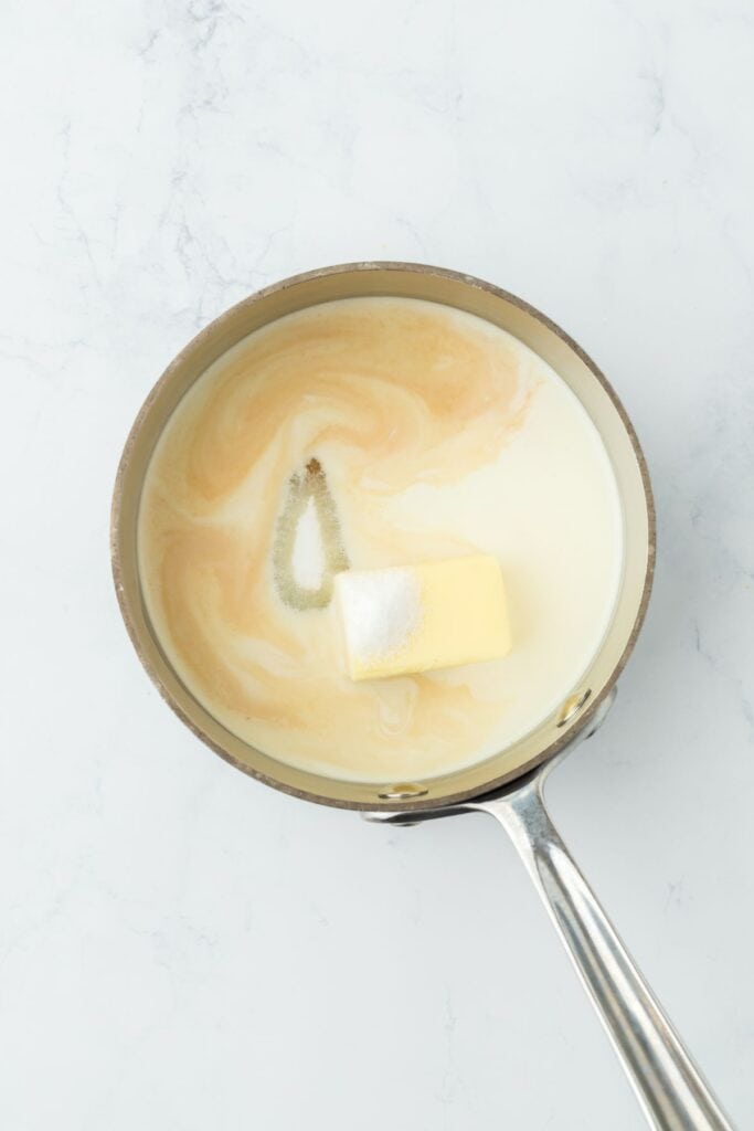 A saucepan with butter, sugar, and half and half beginning to combine