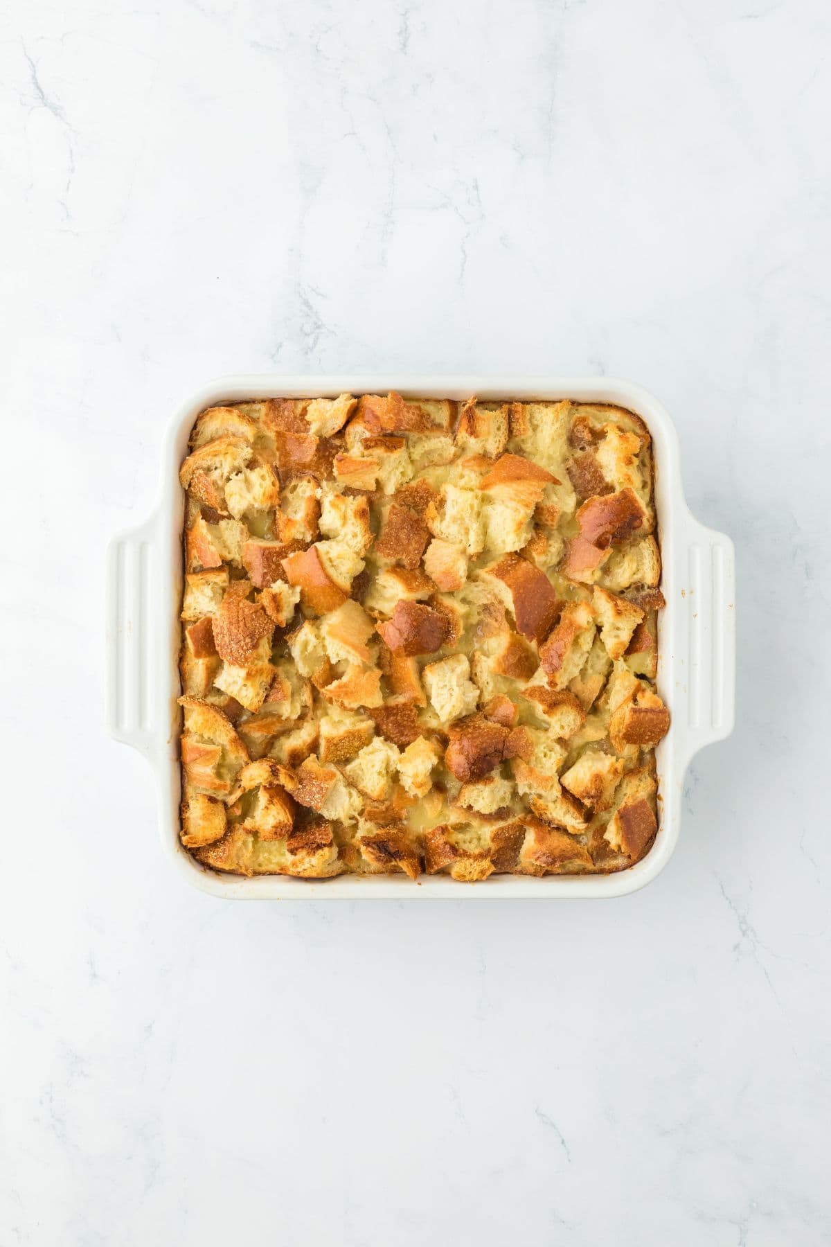 Fully baked eggnog bread pudding in a rectangular white baking dish, golden and crispy on top