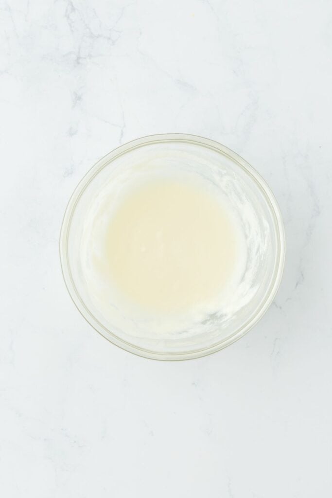 A smooth and creamy glaze mixture in a glass bowl