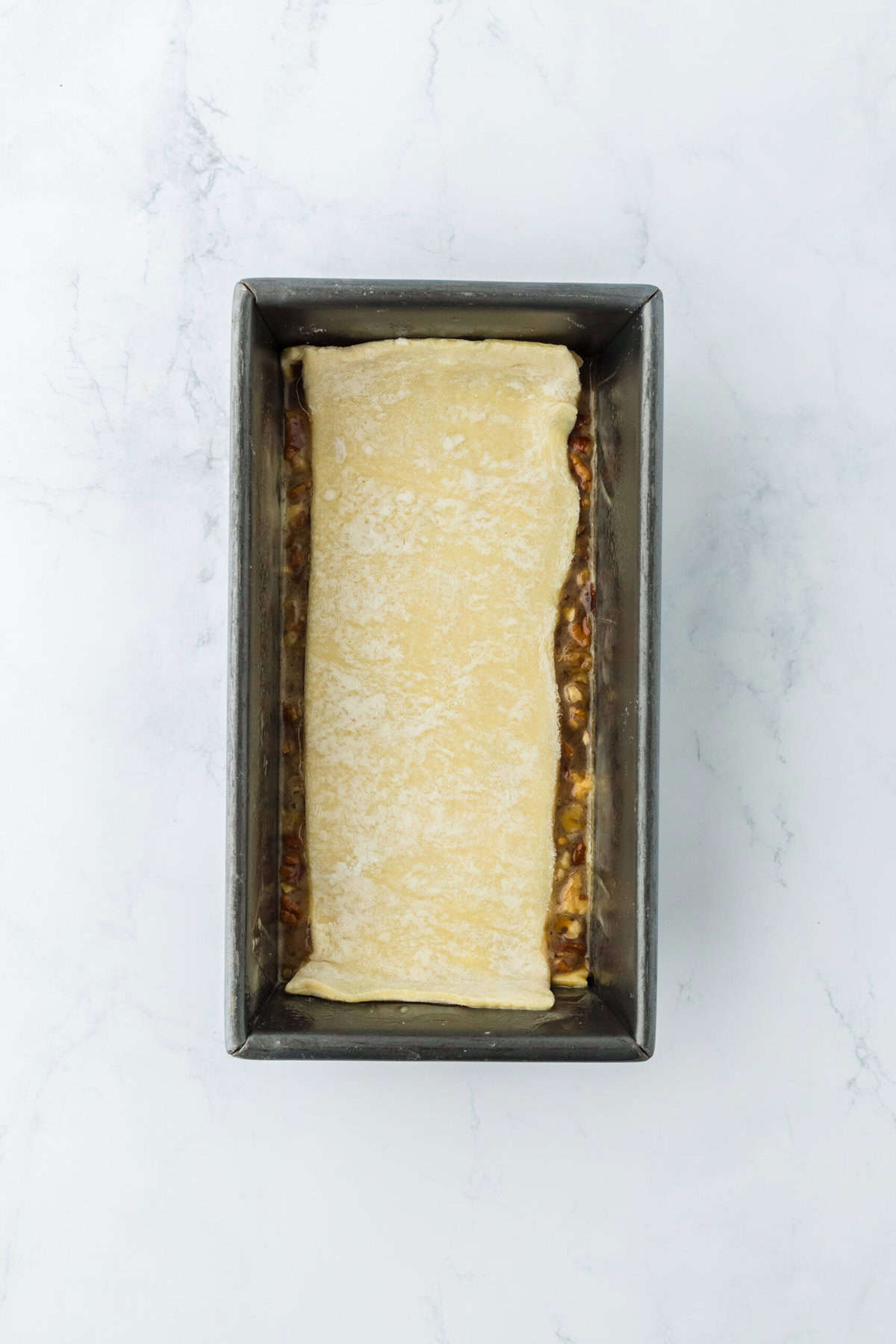 Layer of puff pastry on pecan filling in a loaf pan