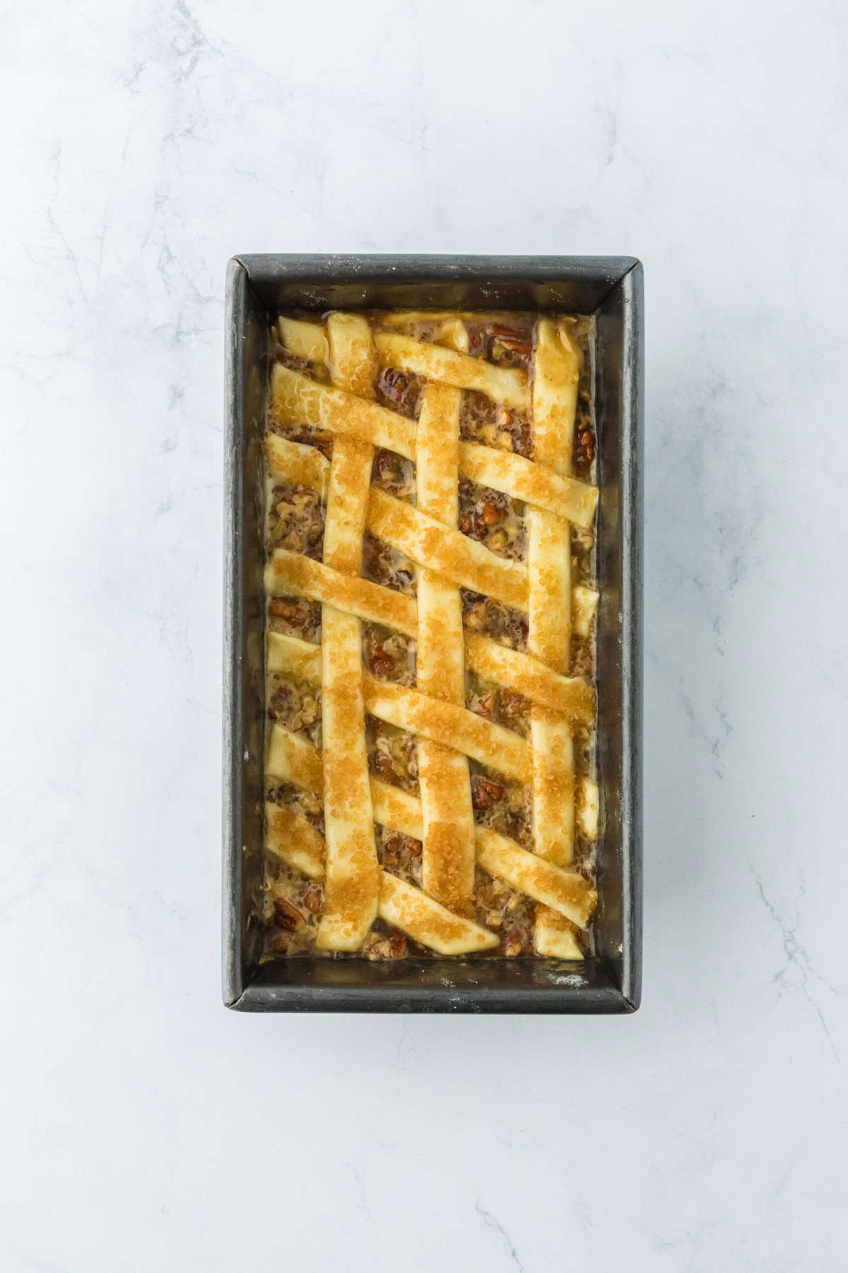 Lattice puff pastry added to pecan cobbler recipe with sugar on top before baking.