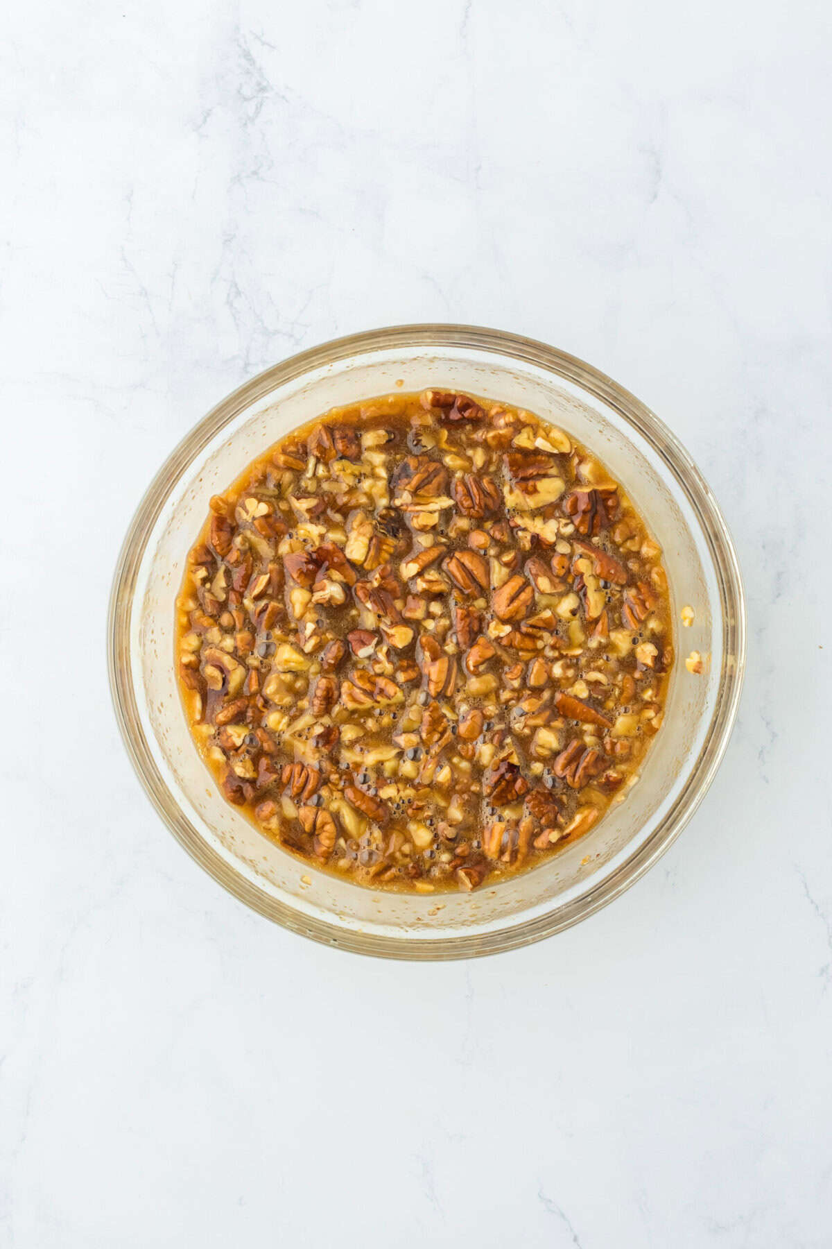 Pecan pie cobbler filling in a glass bowl on white countertop