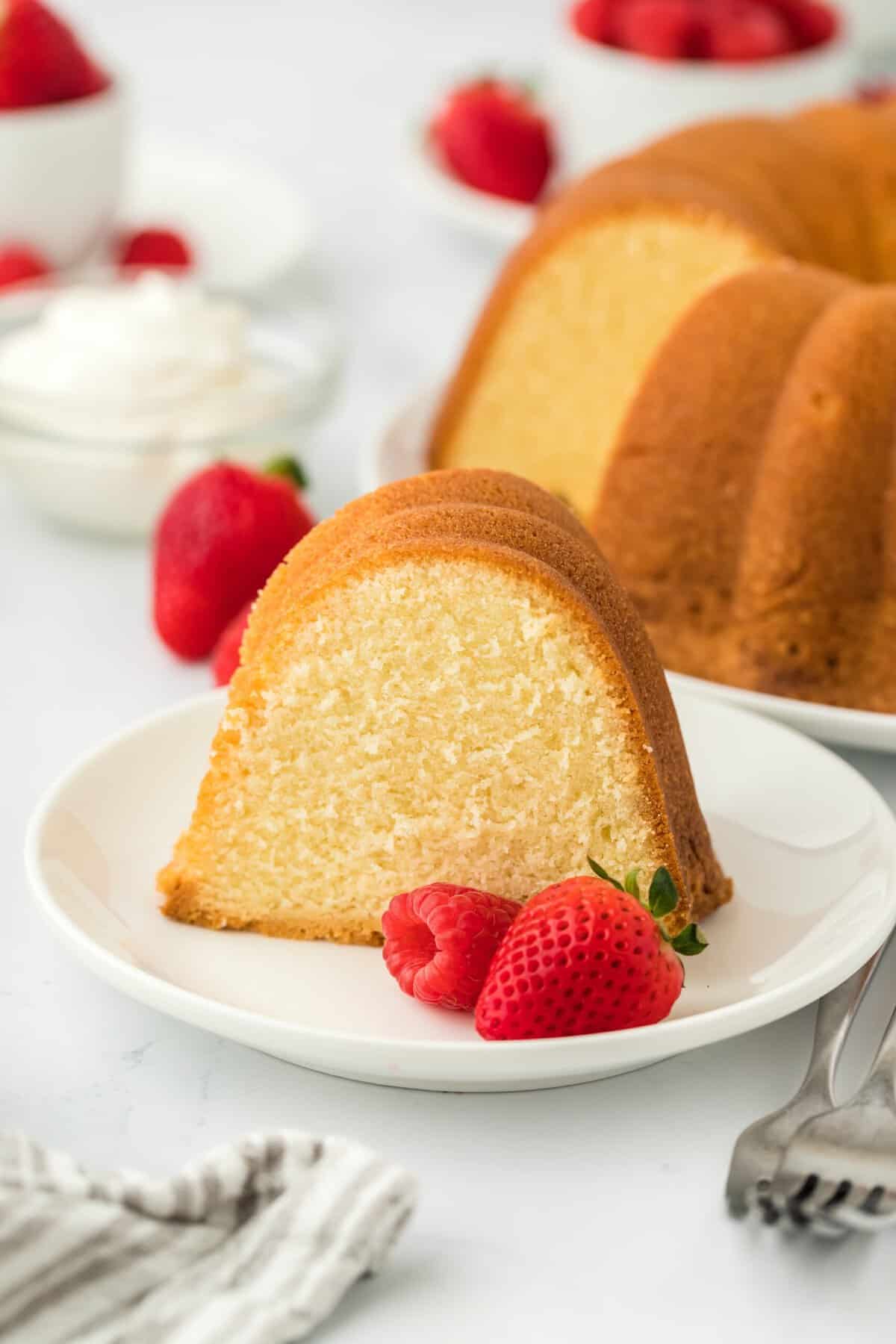 A slice of the best pound cake recipe on a white plate with berries to serve