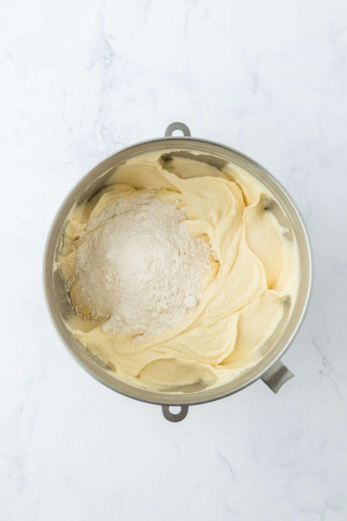 More flour being added to finish a Southern pound cake batter in stand mixer bowl