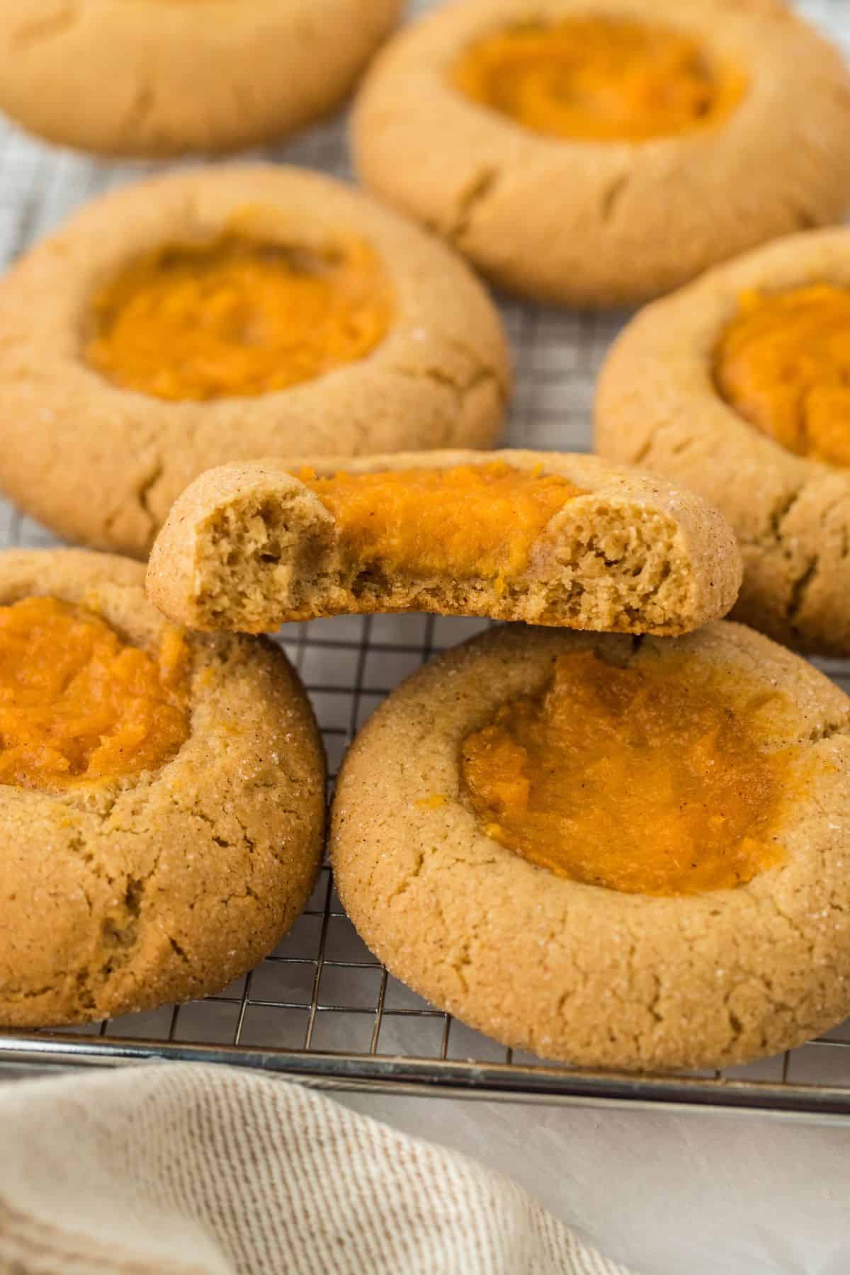 Sweet potato pie cookies on a cooling rack, with one cookie showing a bite taken out