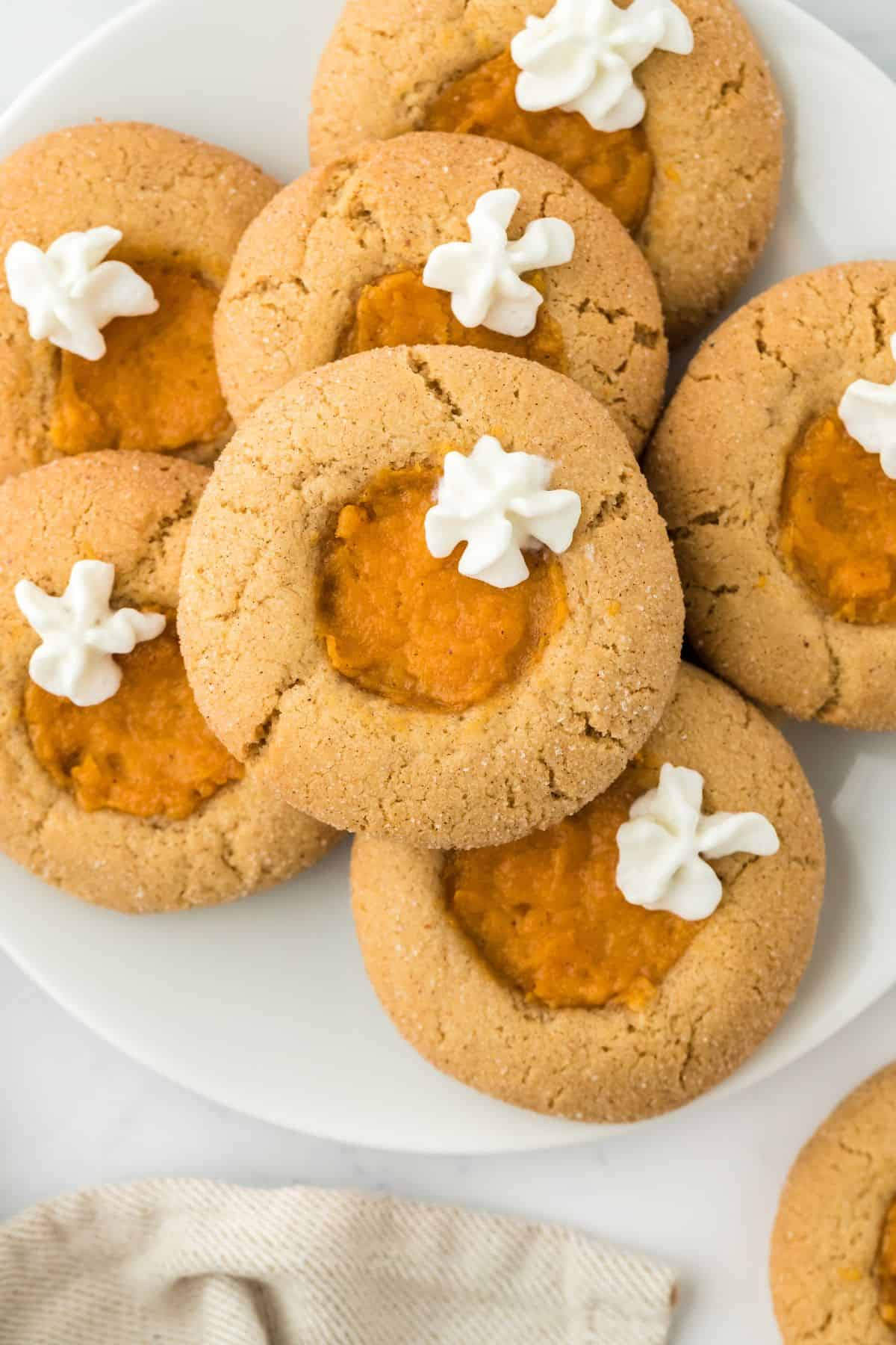 A plate of sweet potato pie cookies, topped with dollops of whipped cream