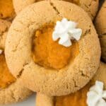 Closeup of sweet potato pie cookies on a plate, topped with dollops of whipped cream