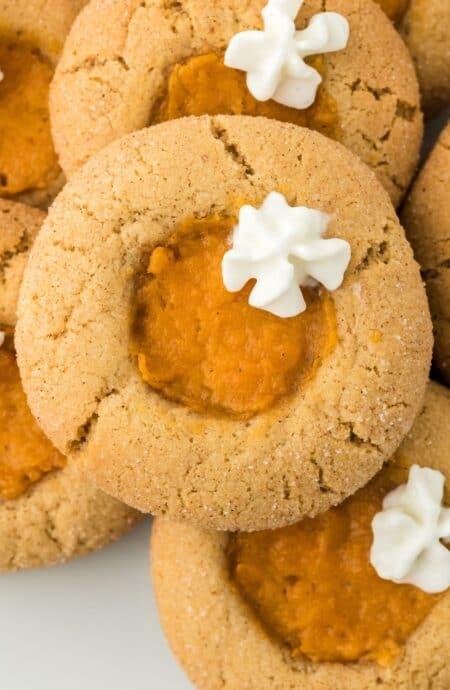 Closeup of sweet potato pie cookies on a plate, topped with dollops of whipped cream