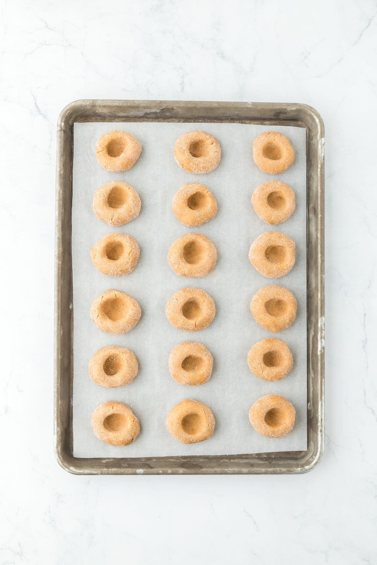 Baking sheet with indentations made in each dough ball for the filling