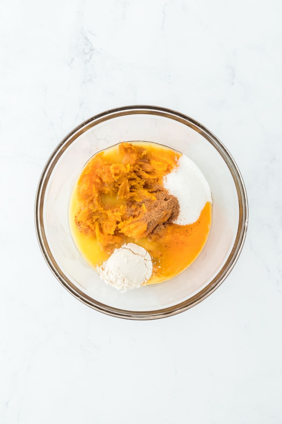 Sweet potato filling ingredients in a glass bowl, including sweet potatoes, eggs, and spices