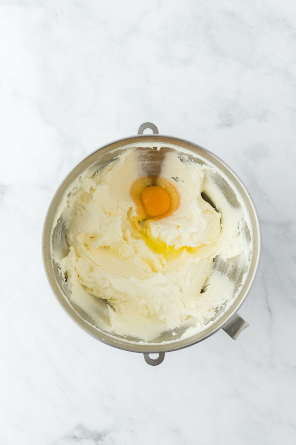 A mixing bowl with creamed butter and sugar and a single egg added