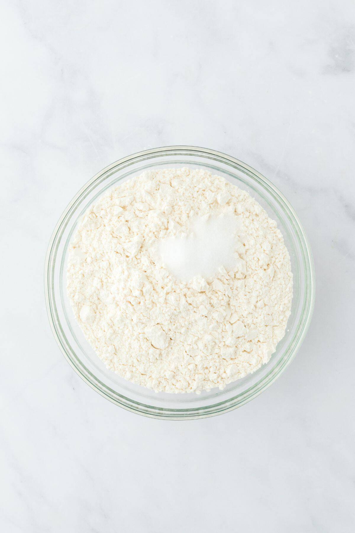 A glass bowl with dry ingredients (flour mixture) before mixing