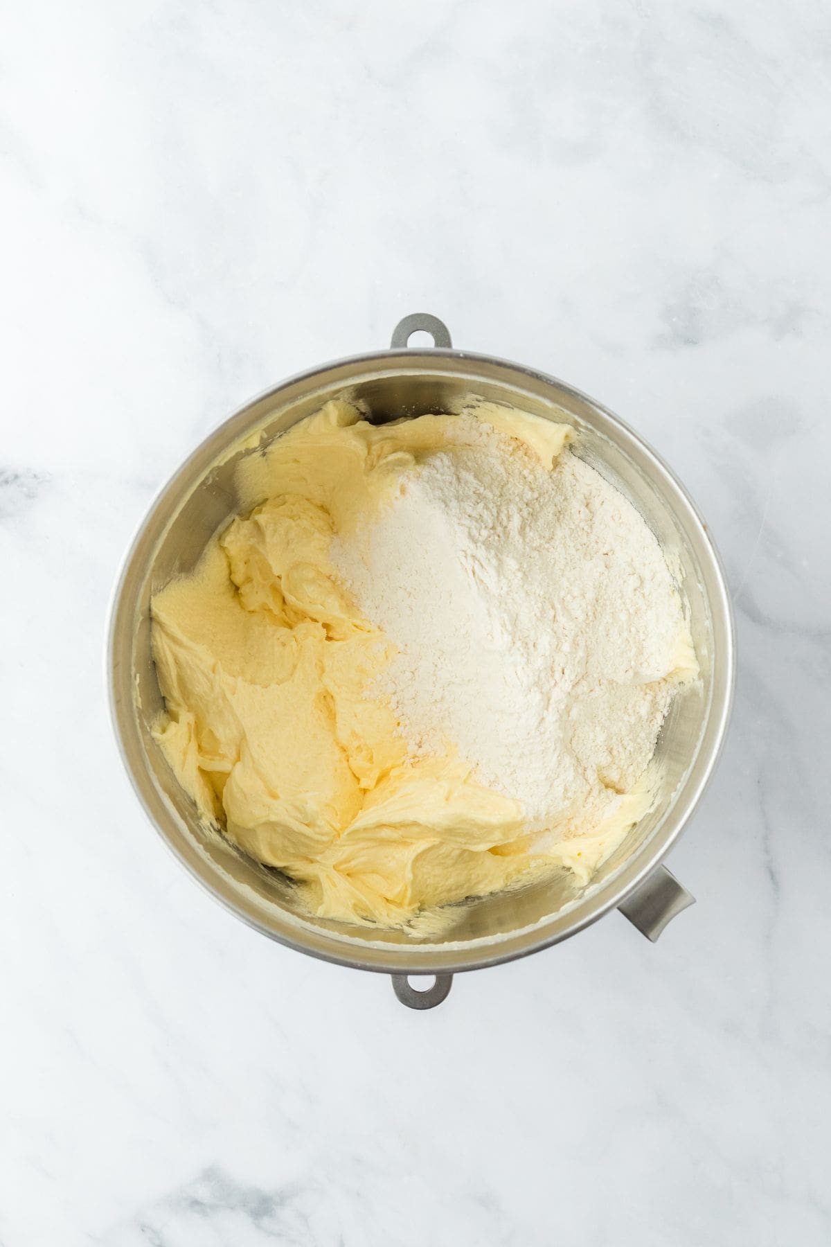 Creamed butter mixture with dry ingredients being added to the bowl