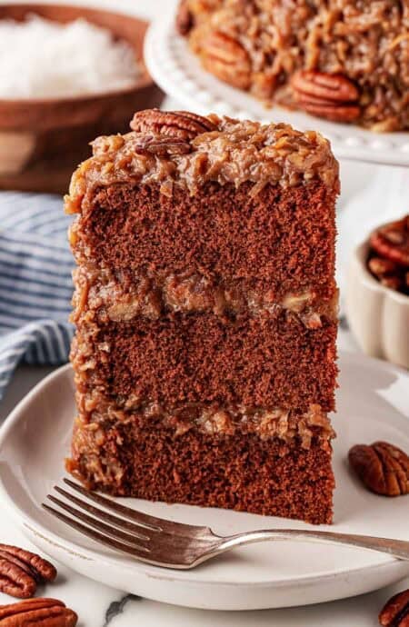 A slice of Gernan chocolate cake on a white plate with silver fork