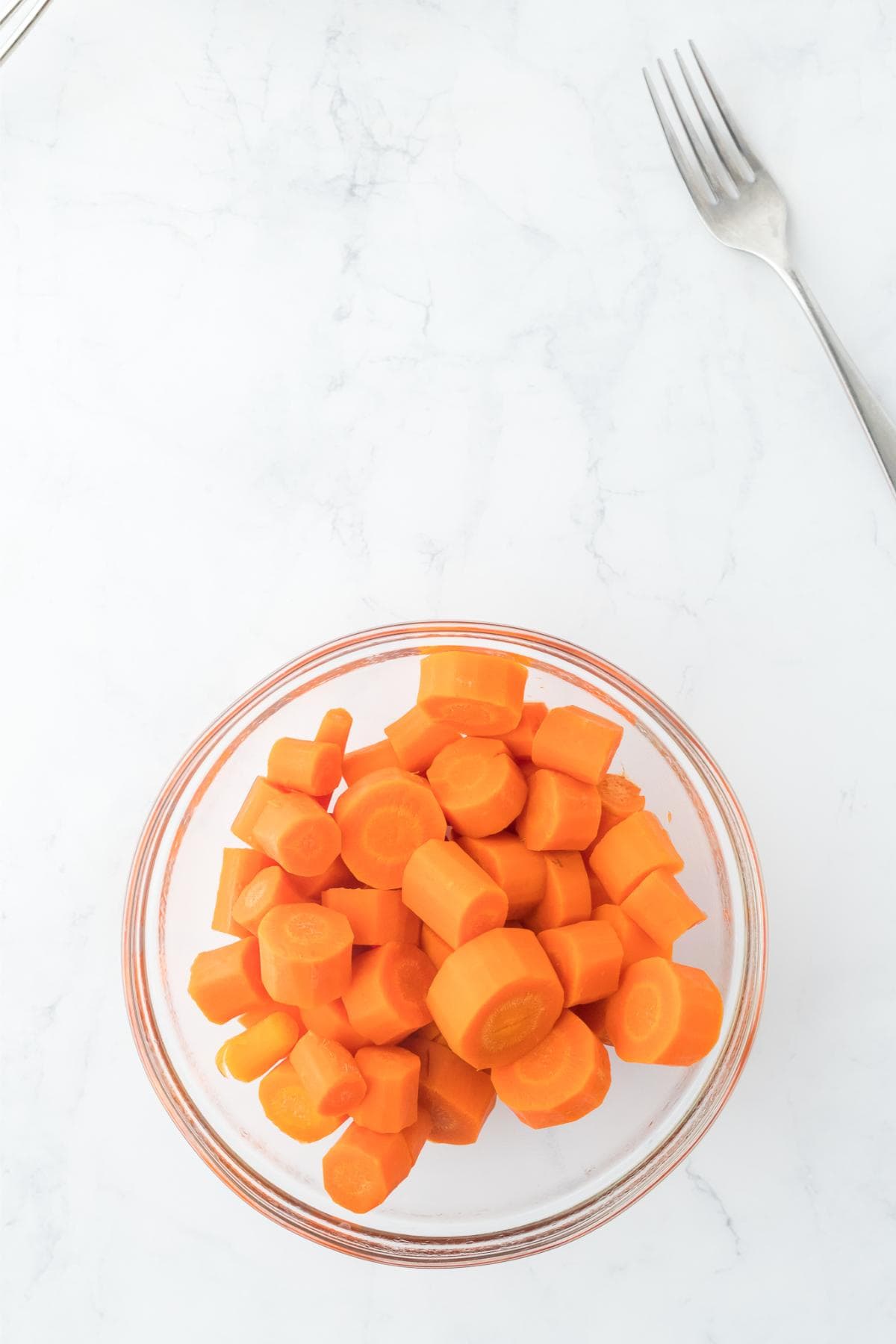 Cooked carrot slices drained and placed in a glass bowl