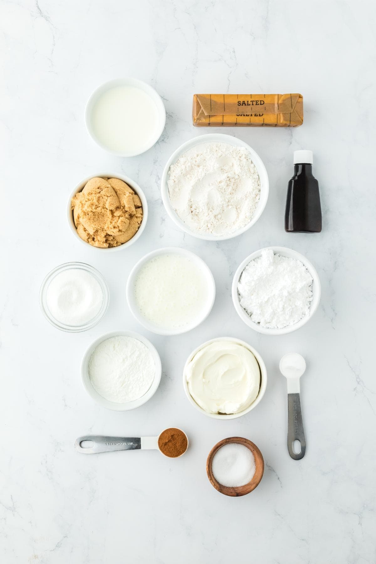 Overhead shot of ingredients to make cinnamon roll butter swim biscuits on a marble surface before mixing and baking