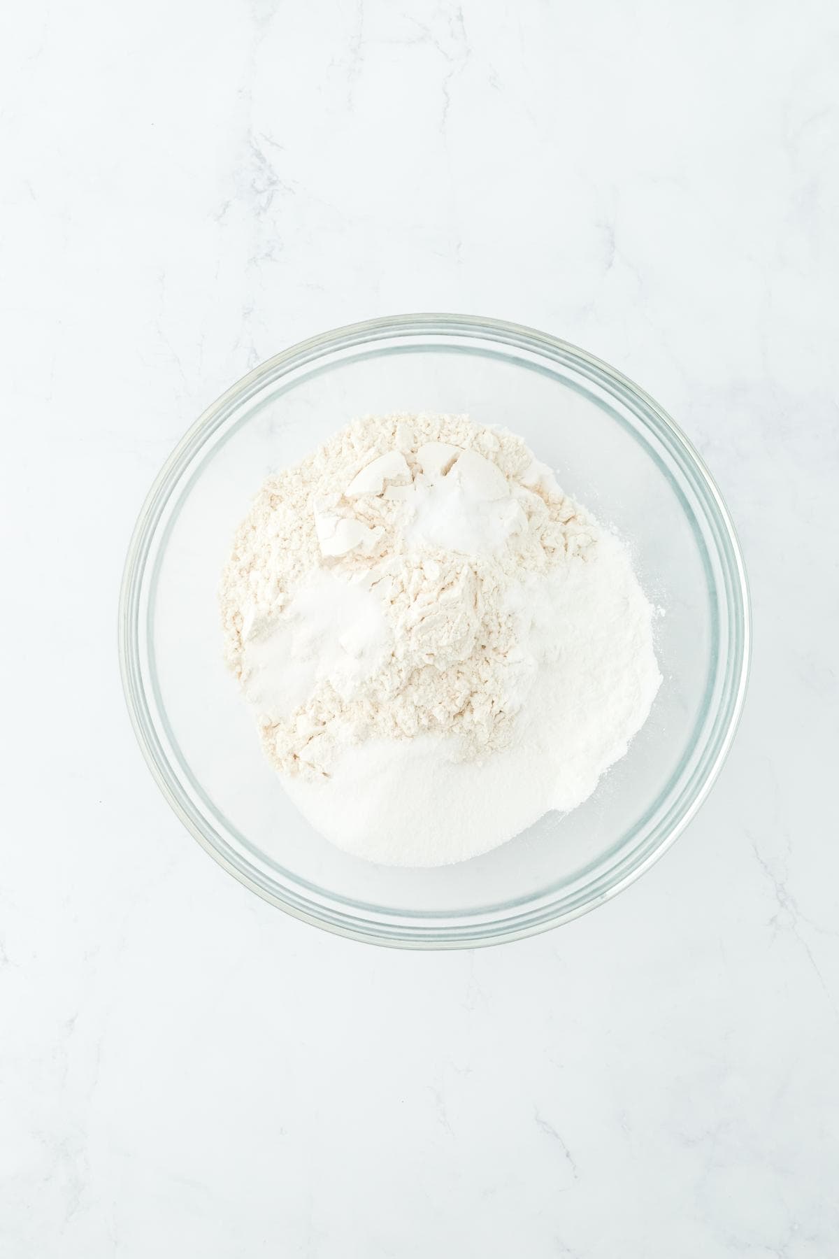 A glass bowl with dry ingredients measured out before mixing