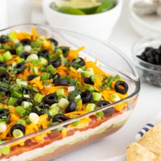 7 layer dip in a glass dish on a white countertop with chips