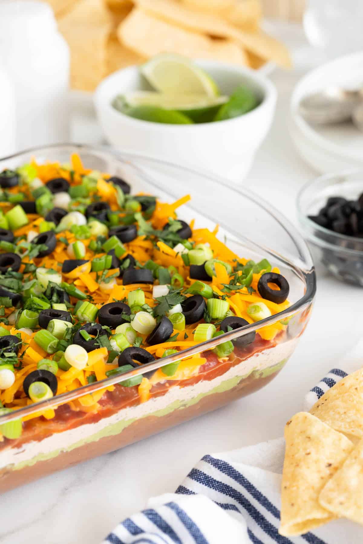 7 layer dip in a glass dish on a white countertop with chips