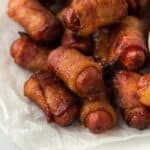 A closeup of bacon wrapped smokies placed on parchment paper