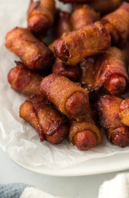 A closeup of bacon wrapped smokies placed on parchment paper