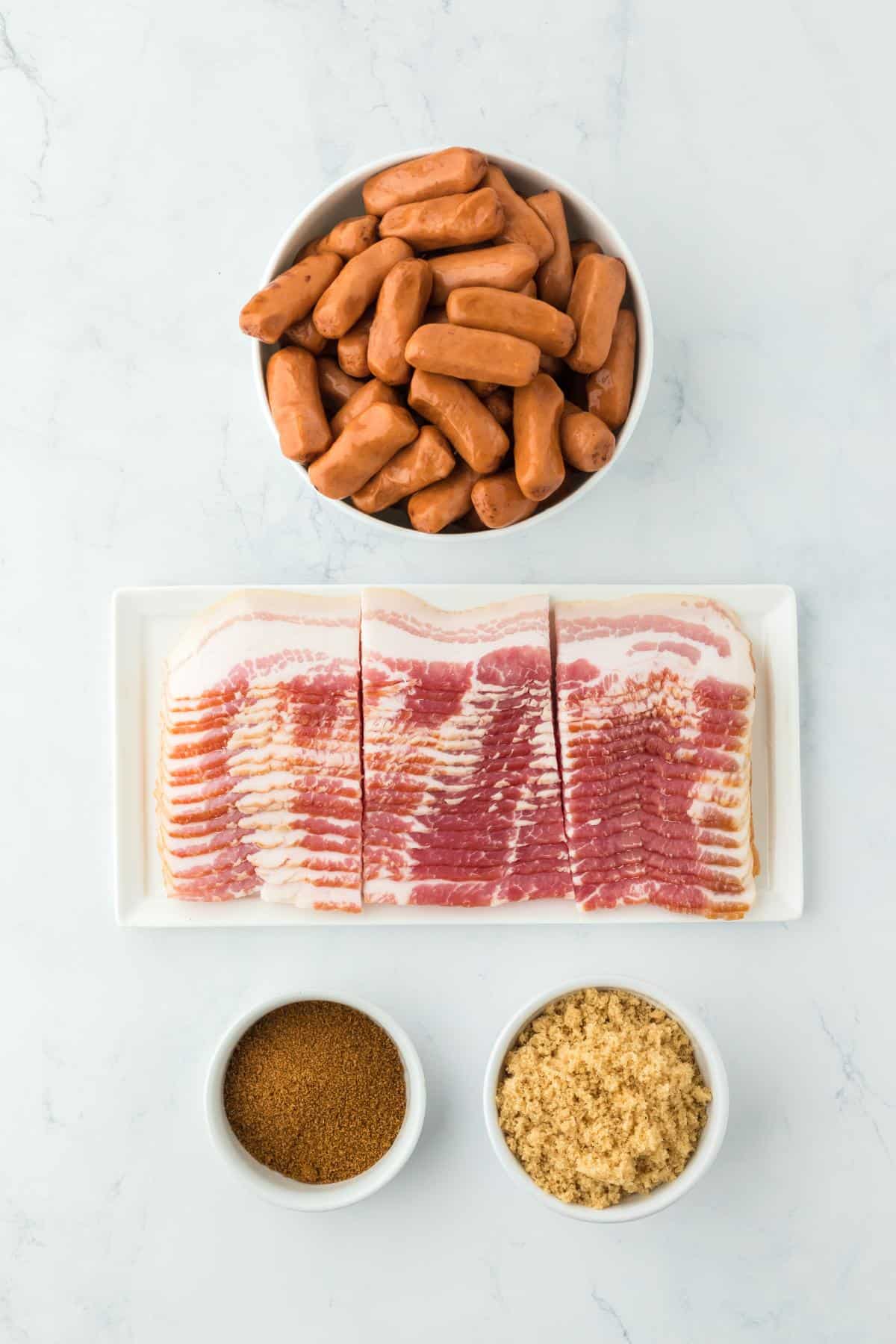 Overhead shot of ingredients for making bacon wrapped smokies on a marble surface before baking