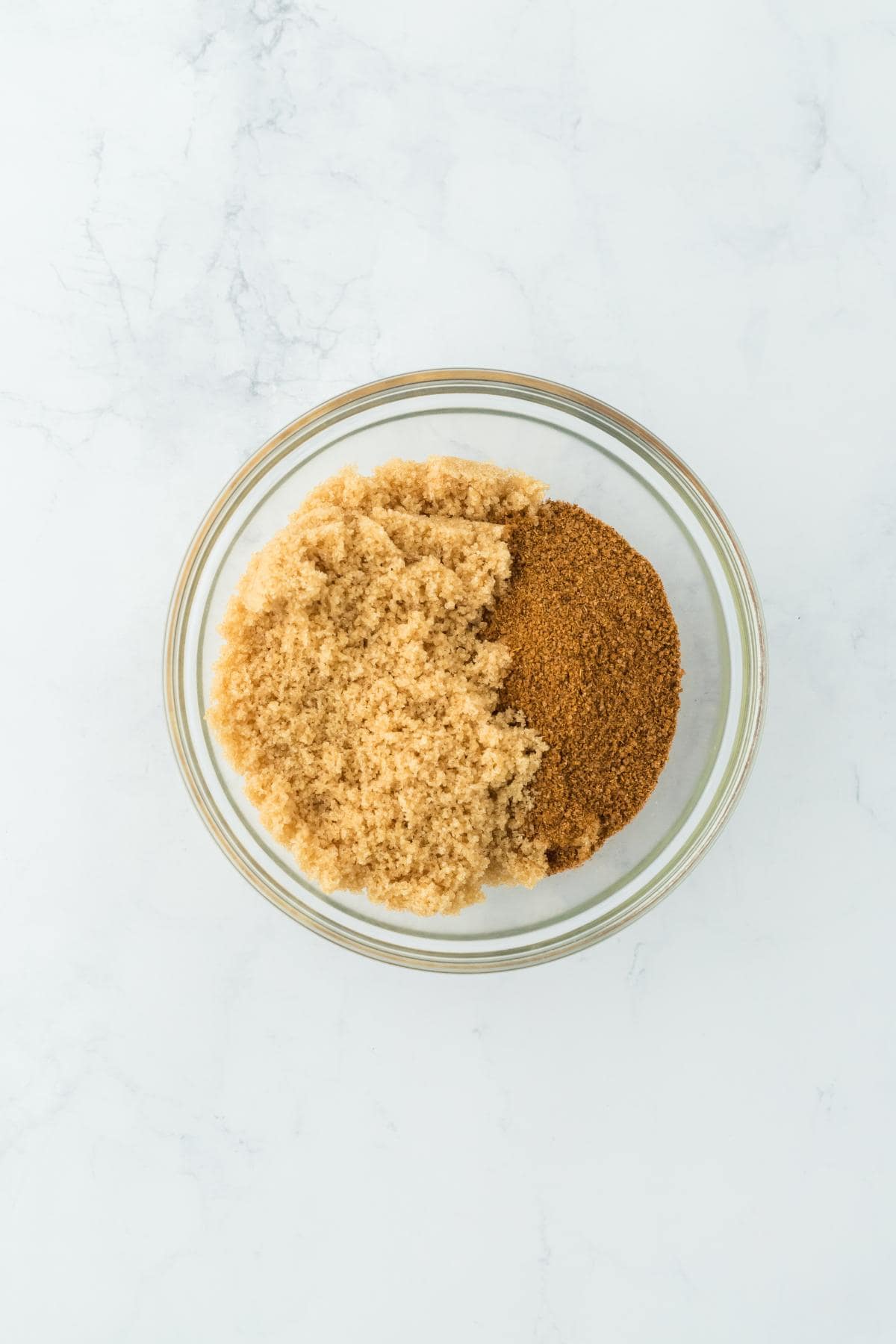 A bowl with brown sugar and Cajun seasoning side by side