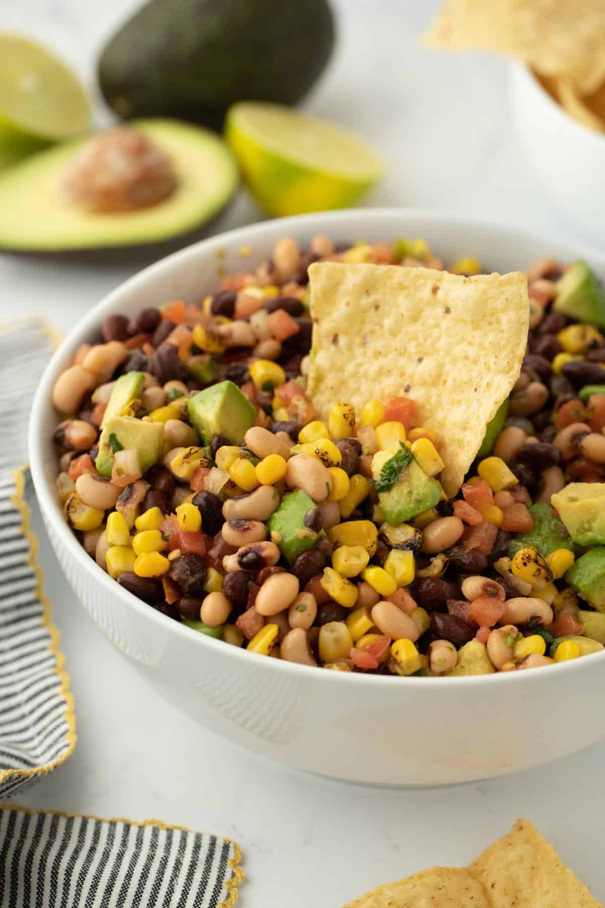 A closeup of cowboy caviar in a bowl with a tortilla chip dipped into it