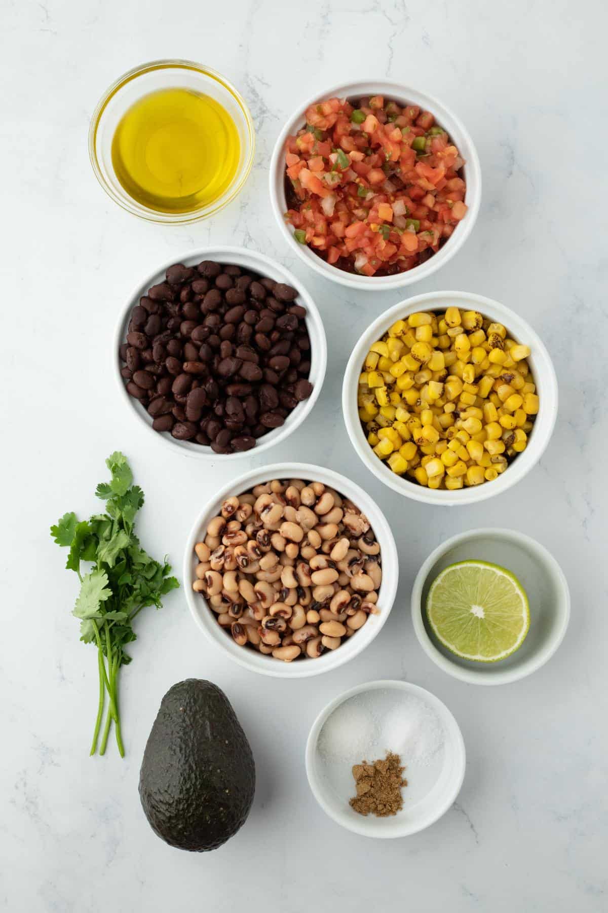 Overhead shot of ingredients for making cowboy caviar on a marble surface before mixing