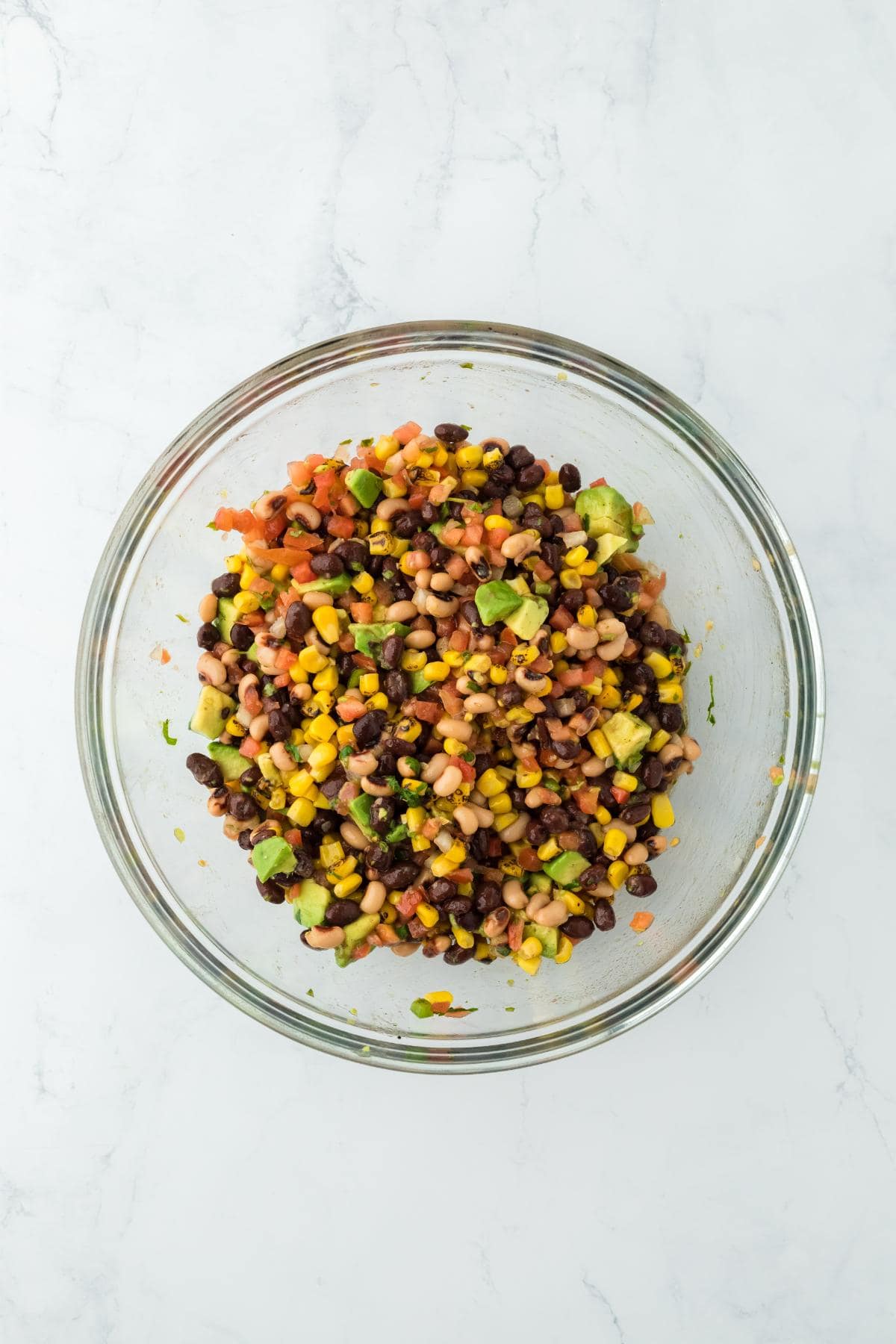 A glass bowl with the cowboy caviar ingredients fully mixed together again