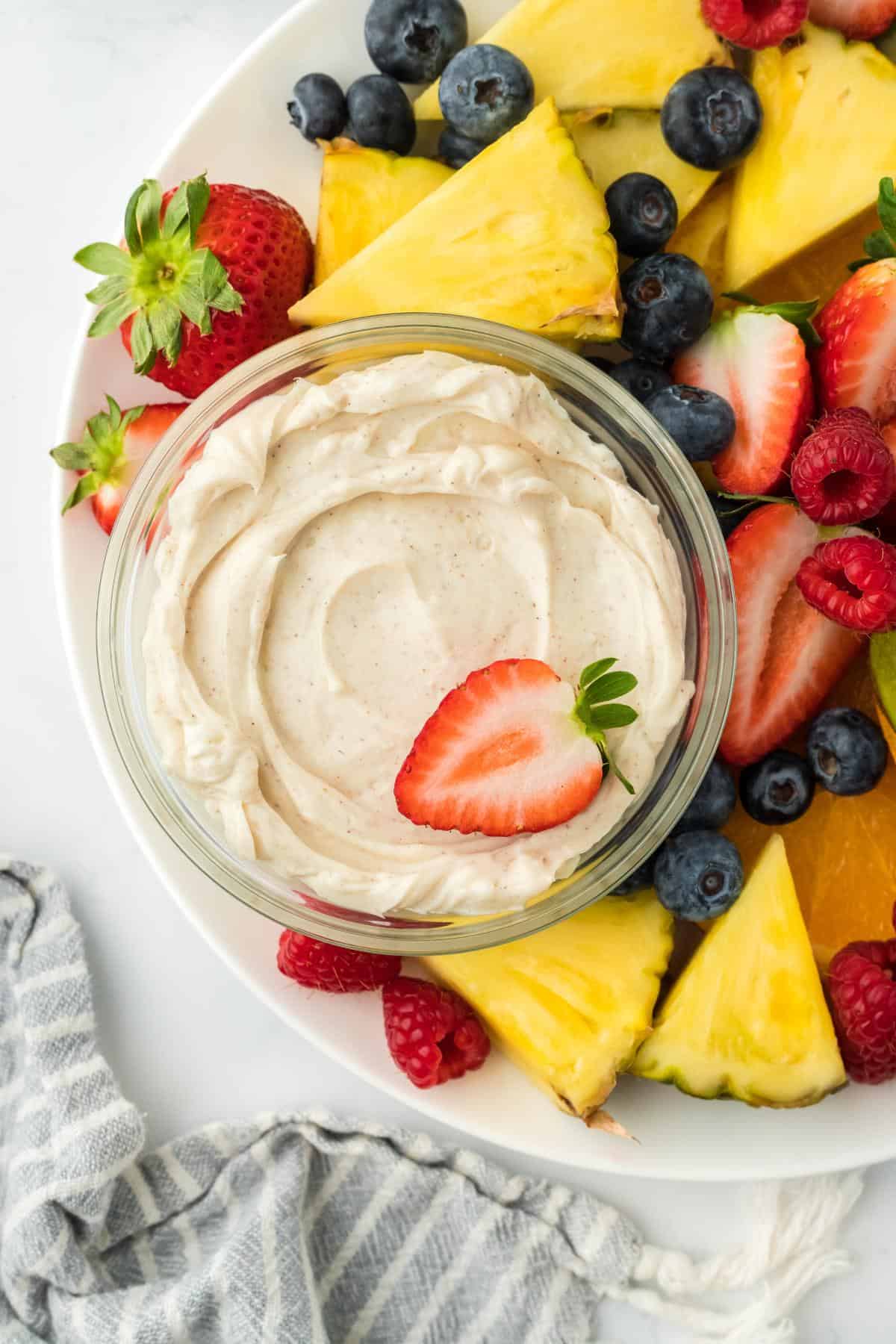 Overhead shot of a fruit platter, highlighting the cream cheese fruit dip in the center, topped with a fresh strawberry slice