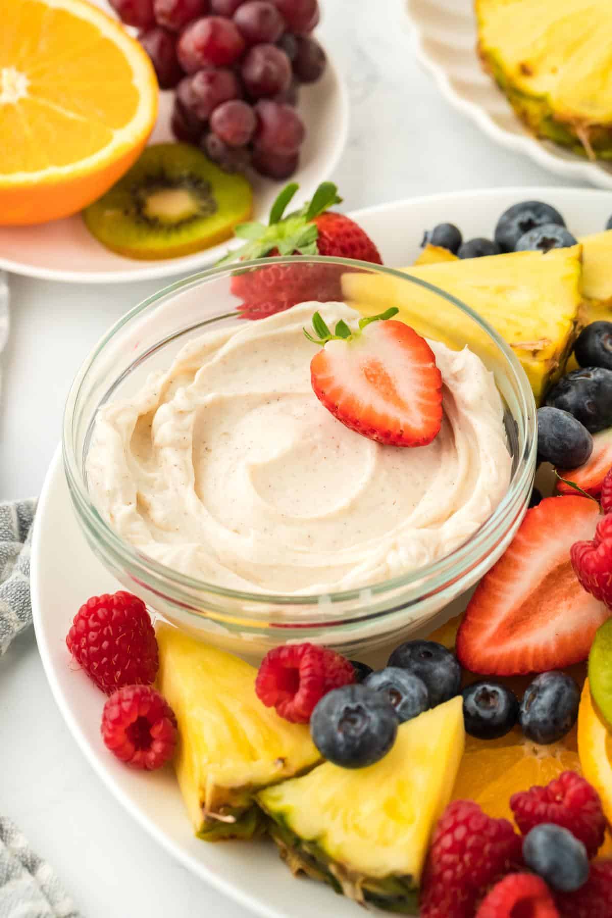 Side angle of the cream cheese fruit dip surrounded by colorful fruit