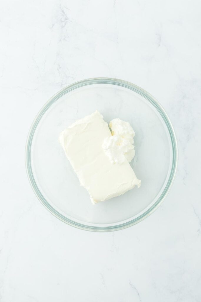 Glass mixing bowl with cream cheese and whipped cream added