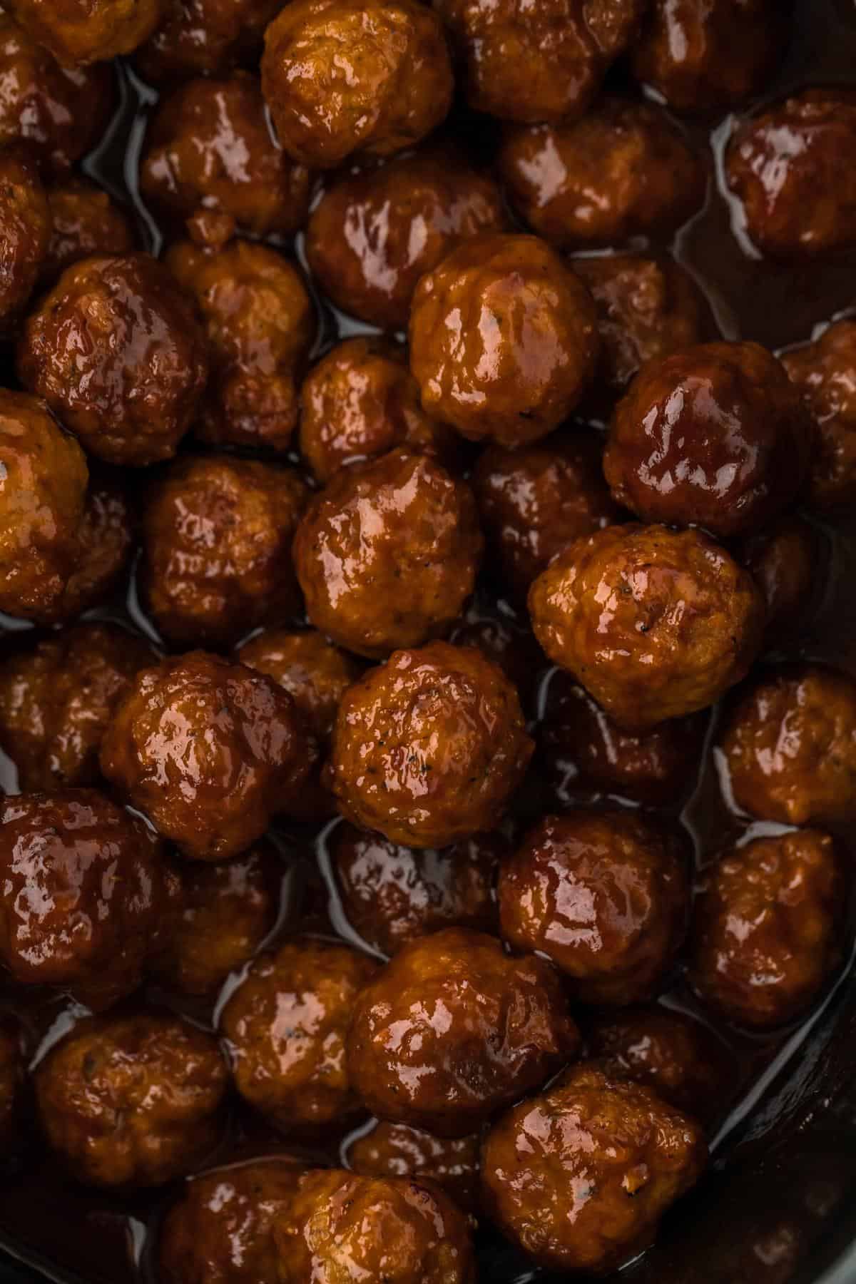 Overhead view of grape jelly meatballs on the slow cooker with sauce pooling around them, ready to be served