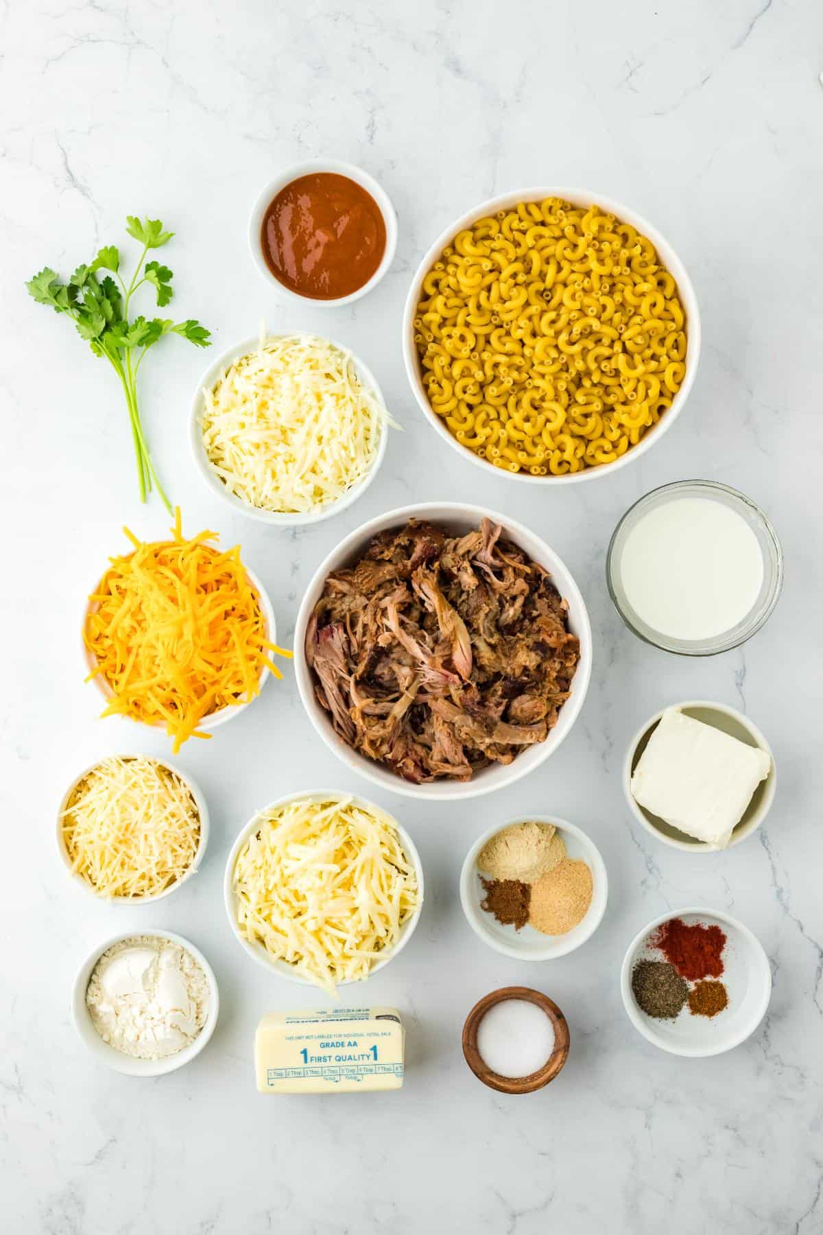 Overhead shot of ingredients for making pulled pork mac and cheese on a marble surface before cooking