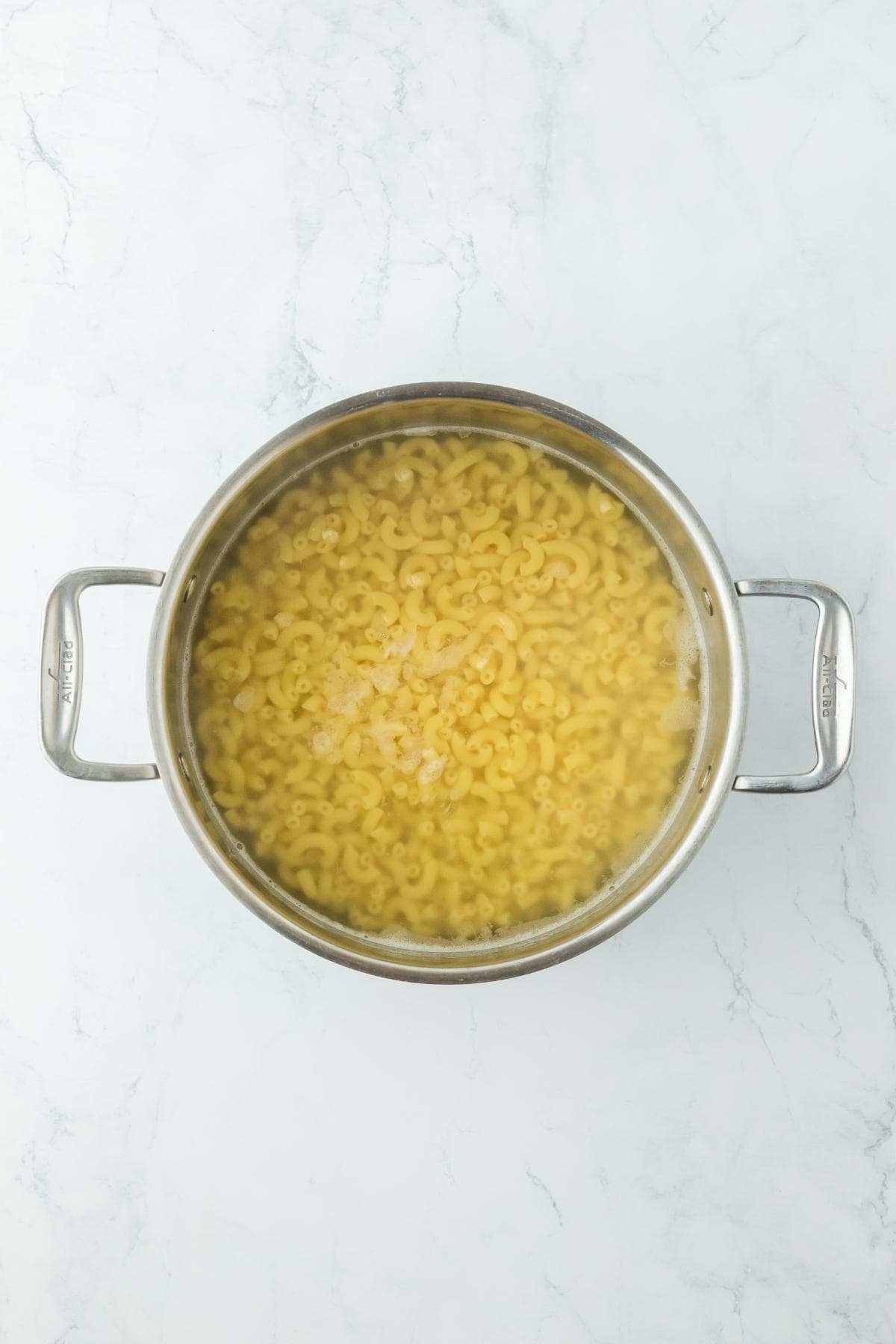 A large pot filled with cooked elbow macaroni submerged in water