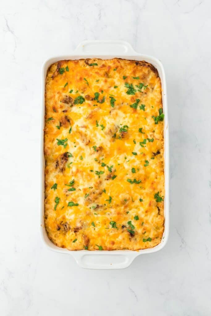 The fully baked pulled pork mac and cheese in a casserole dish, golden brown and garnished with parsley