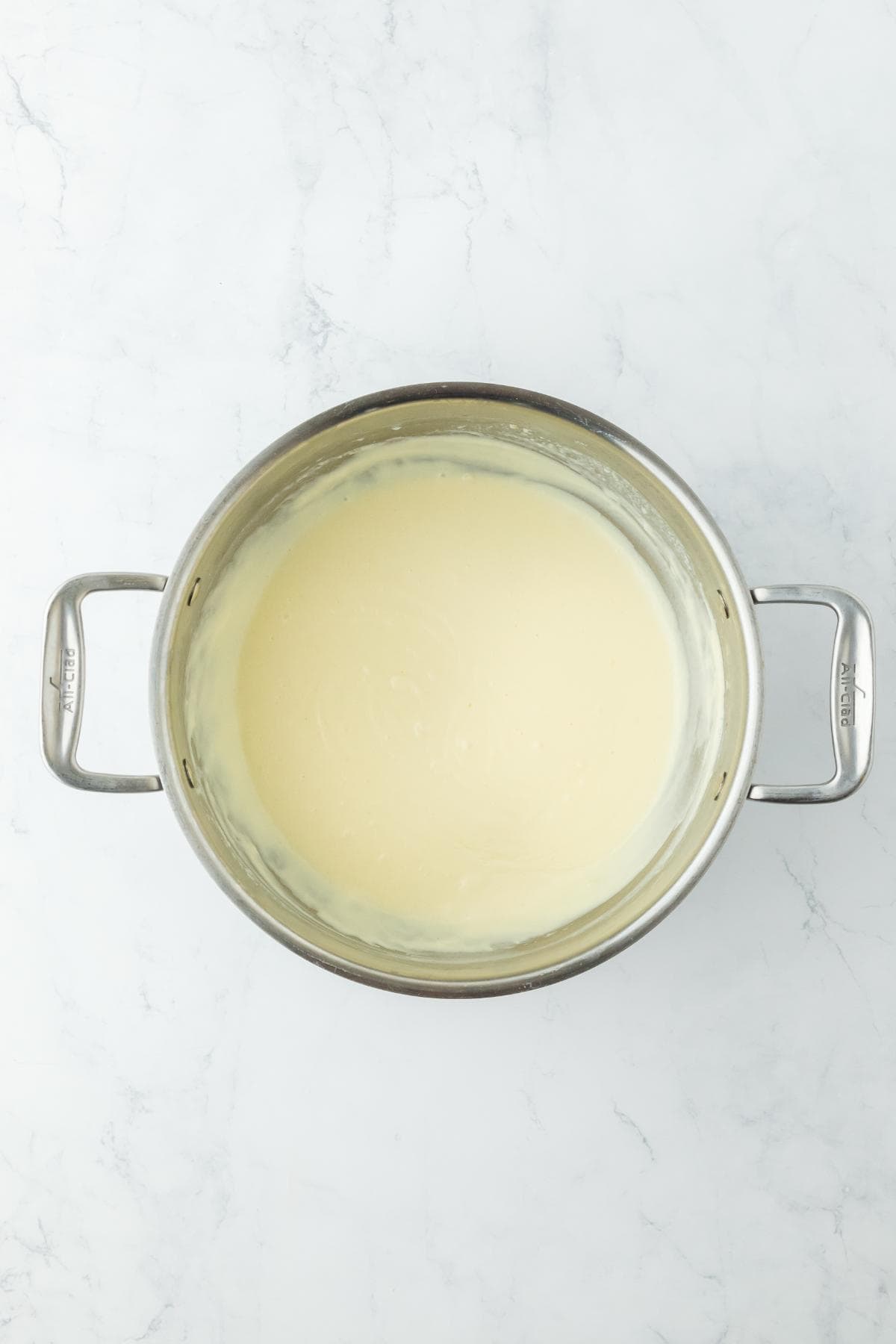 A pot with a smooth, creamy white roux, stirred to form the base of a sauce