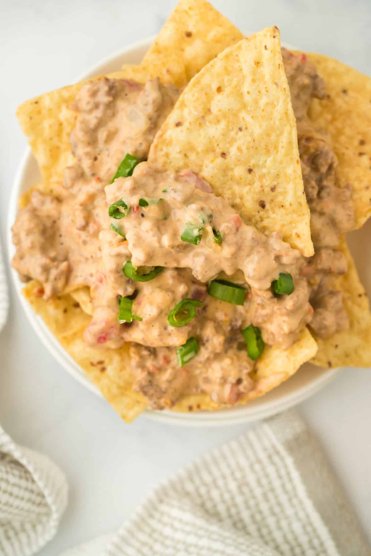 Rotel cheese dip in a large white bowl with tortilla chips dipped in ready to serve