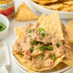 A white bowl of rotel dip with tortilla chips inside ready to serve on white background