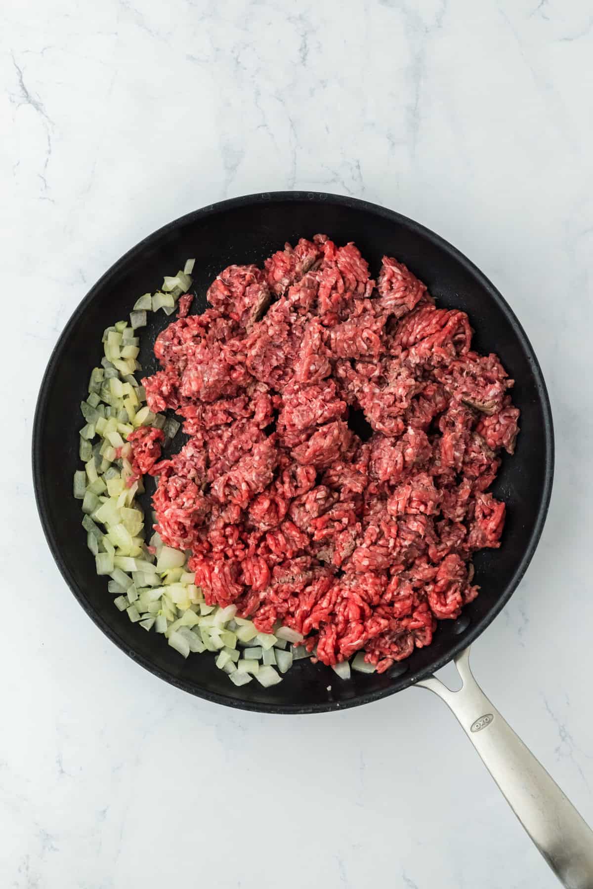 Onions and ground beef added to a skillet browning