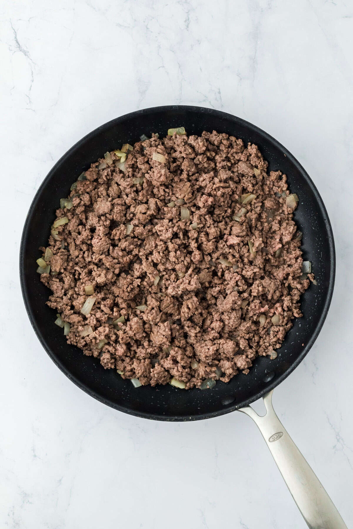 Browned ground beef and onion in a skillet.