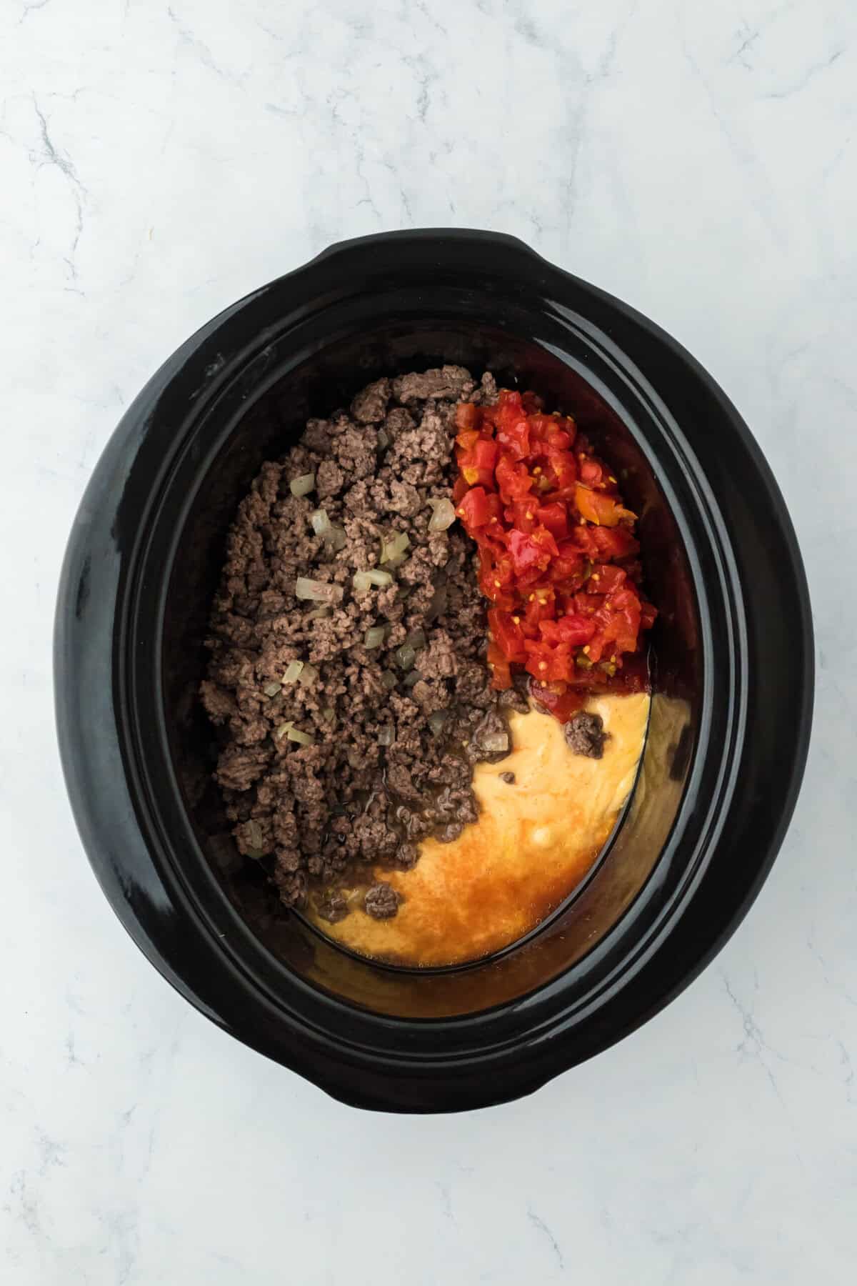 Ground beef, melted cheese and tomatoes in a slow cooker