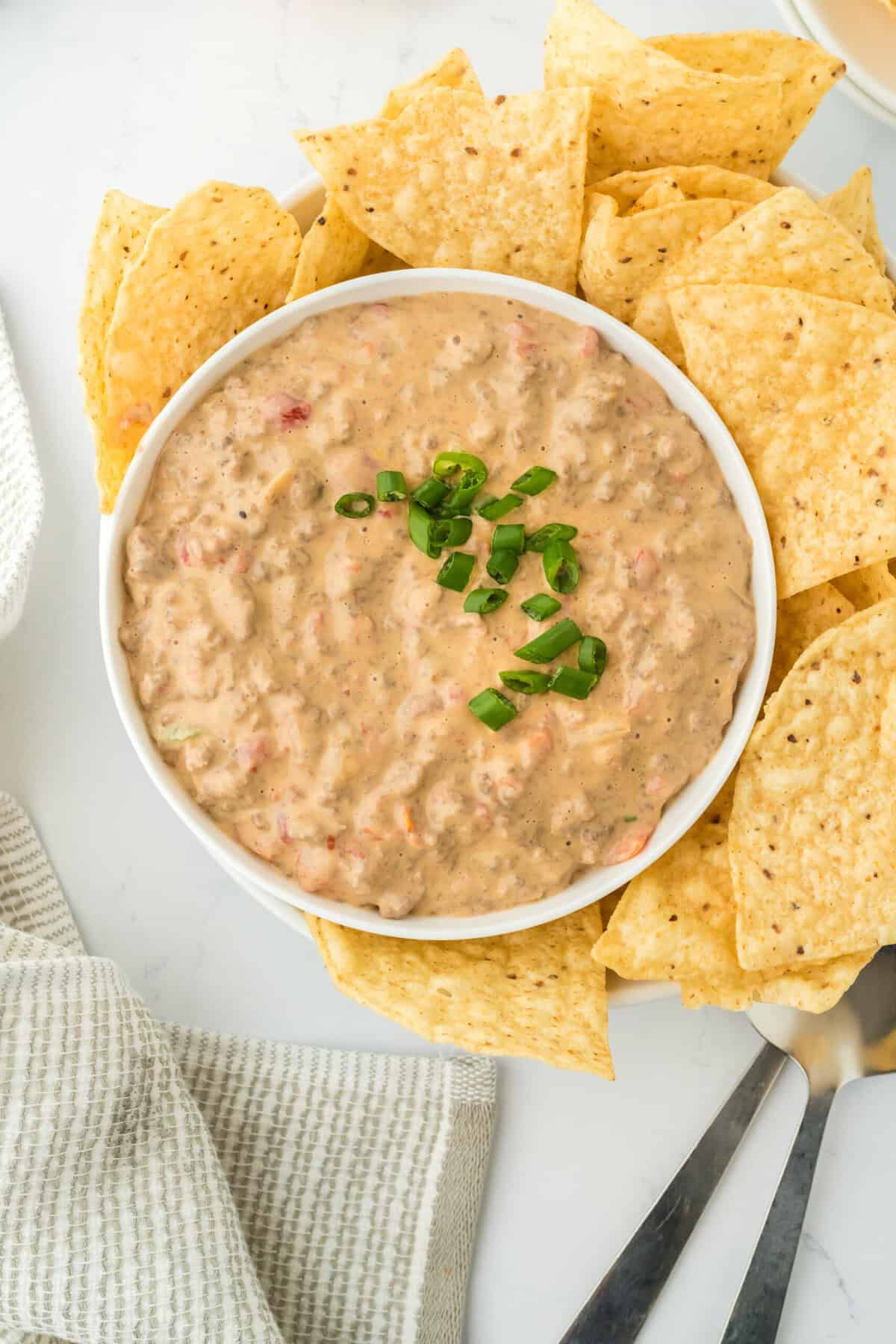 A large bowl of Velveeta rotel dip recipe ready to serve with tortilla chips around it