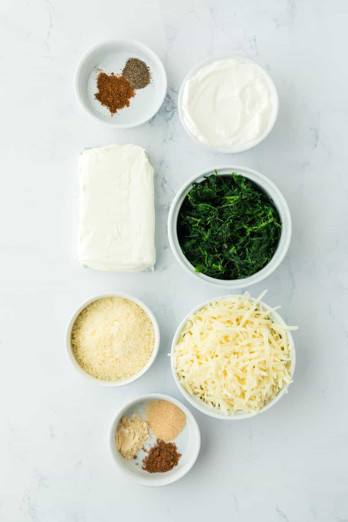 Overhead shot of ingredients for making spinach dip on a marble surface before mixing