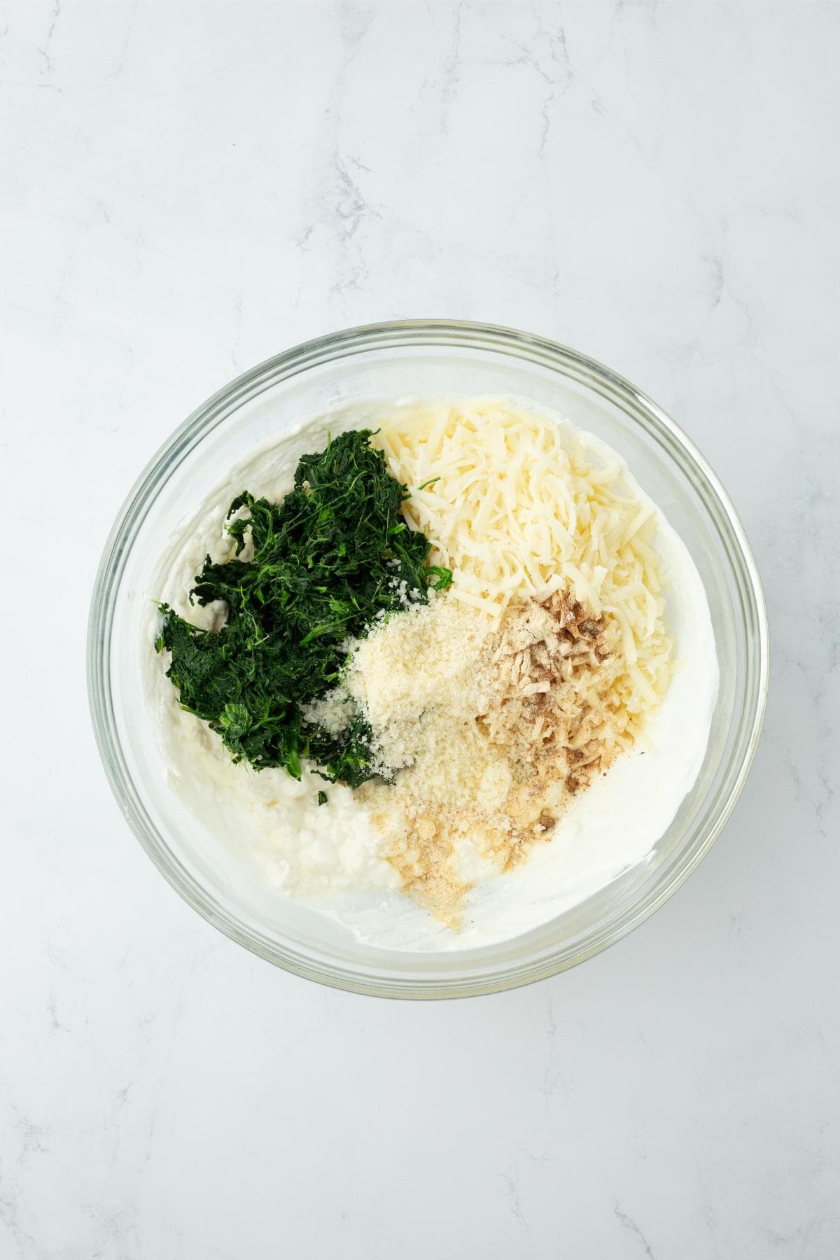 Bowl with spinach, cheese, and seasonings added to cream cheese mixture before combining