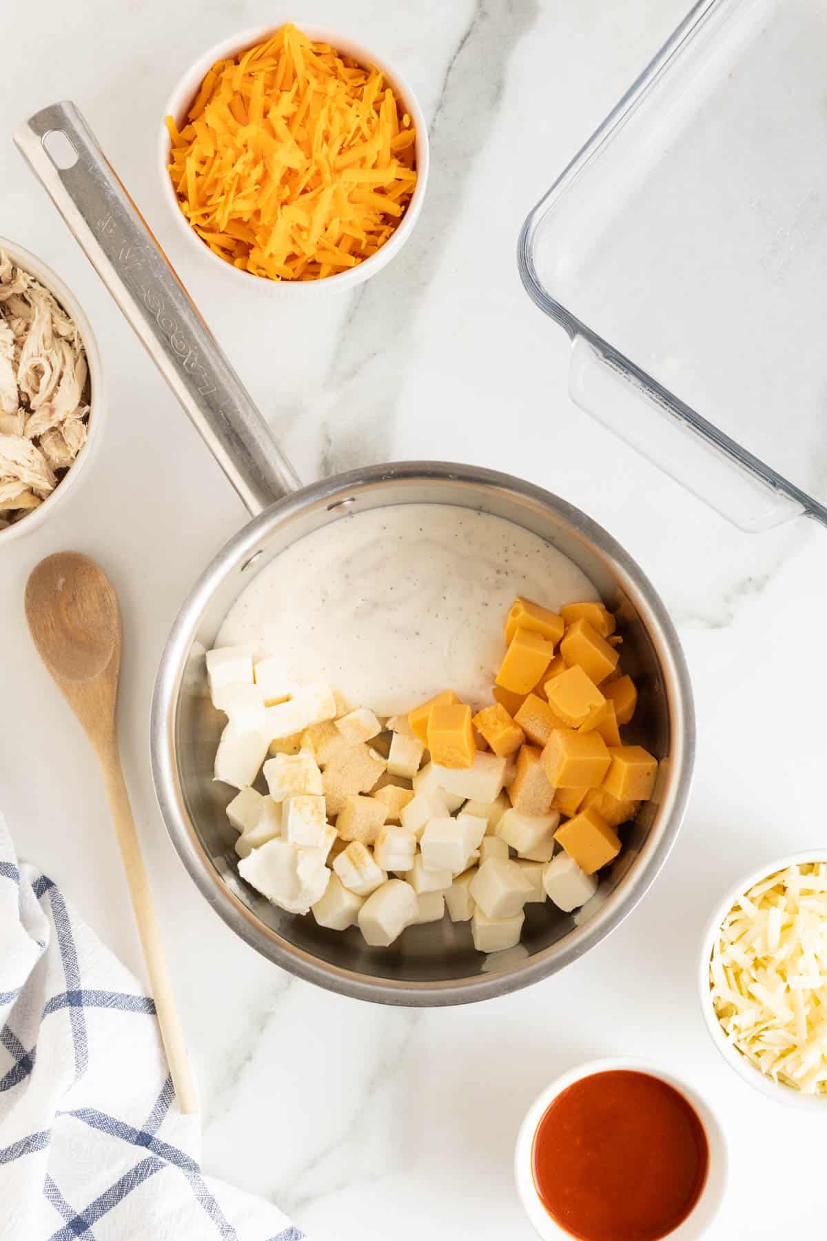 Cheeses added to a saucepan with spices and ranch dressing