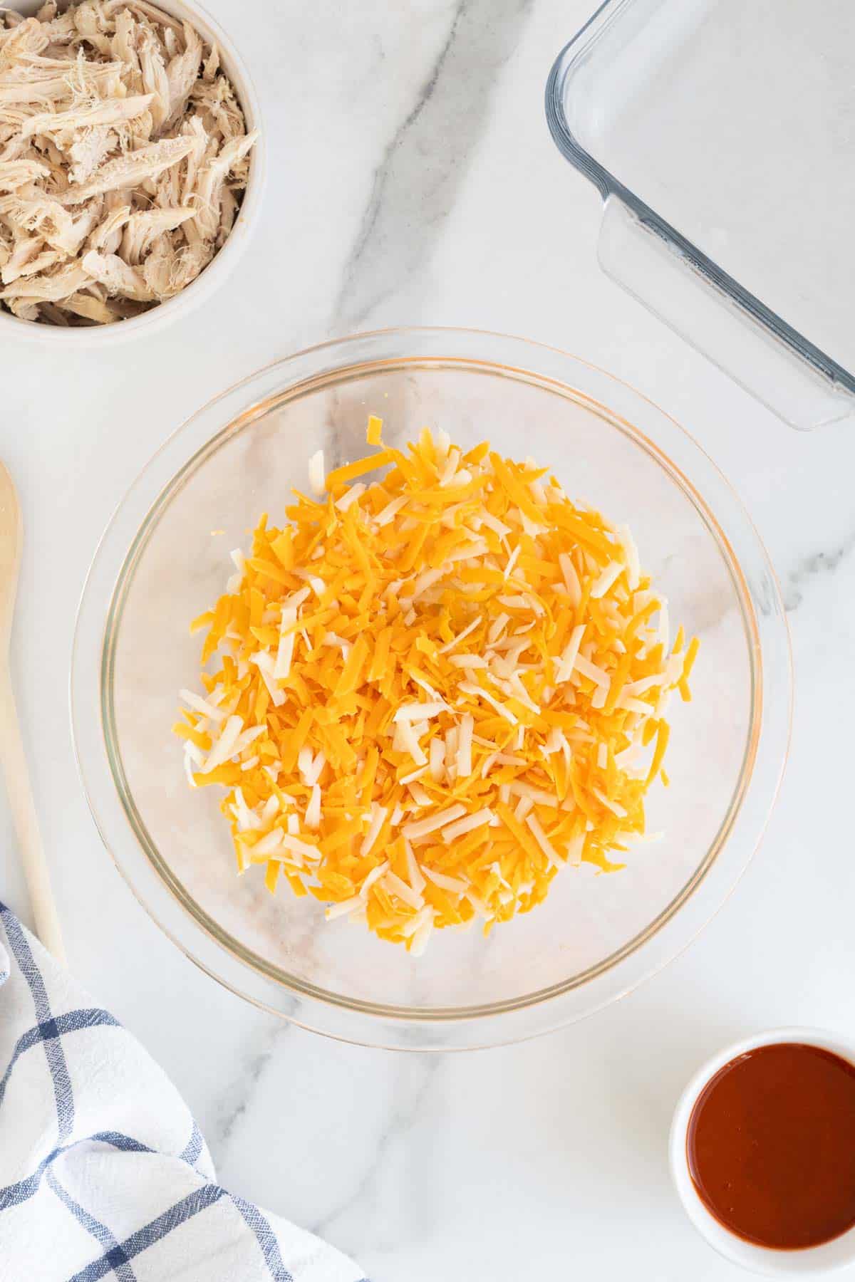 Shredded cheeses add to a glass bowl