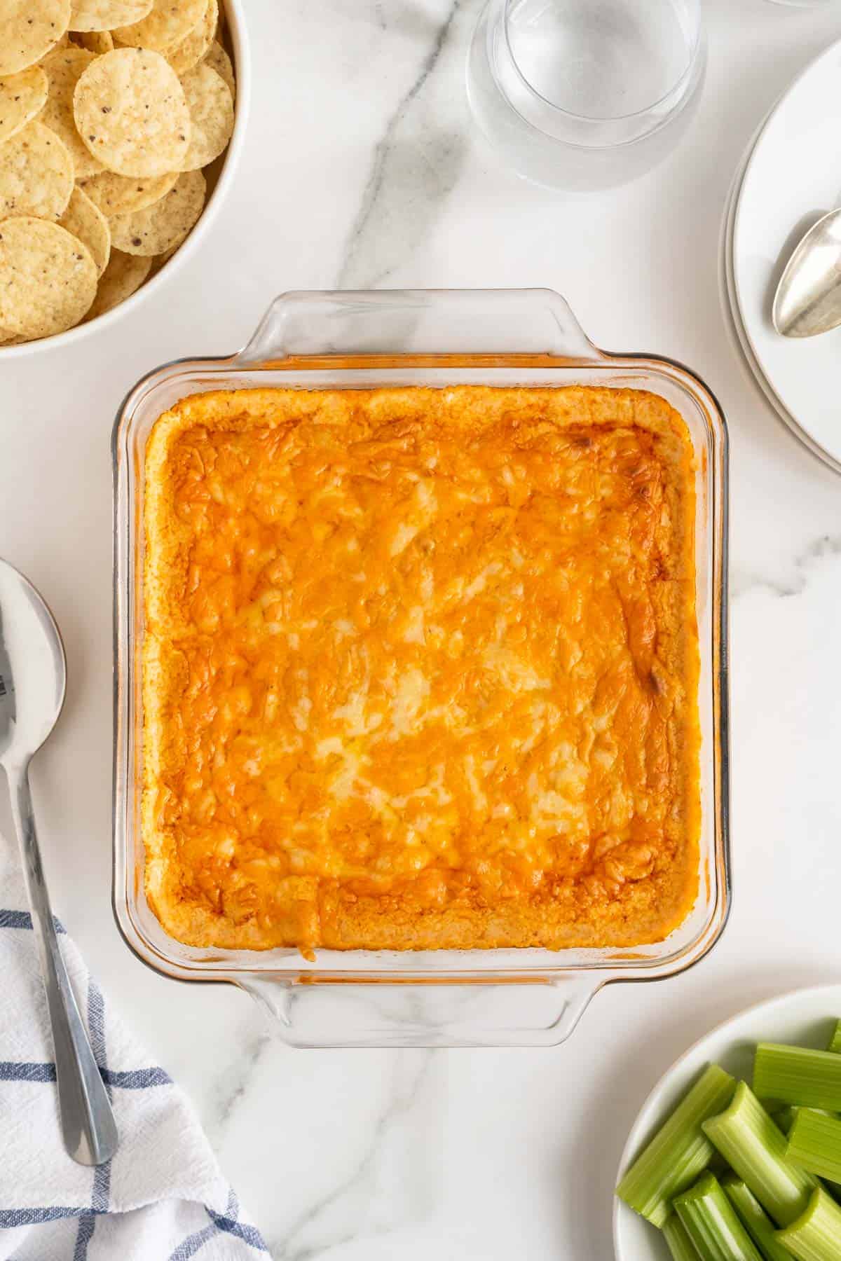 Baked buffalo dip in a casserole dish after baking with tortilla chips around.