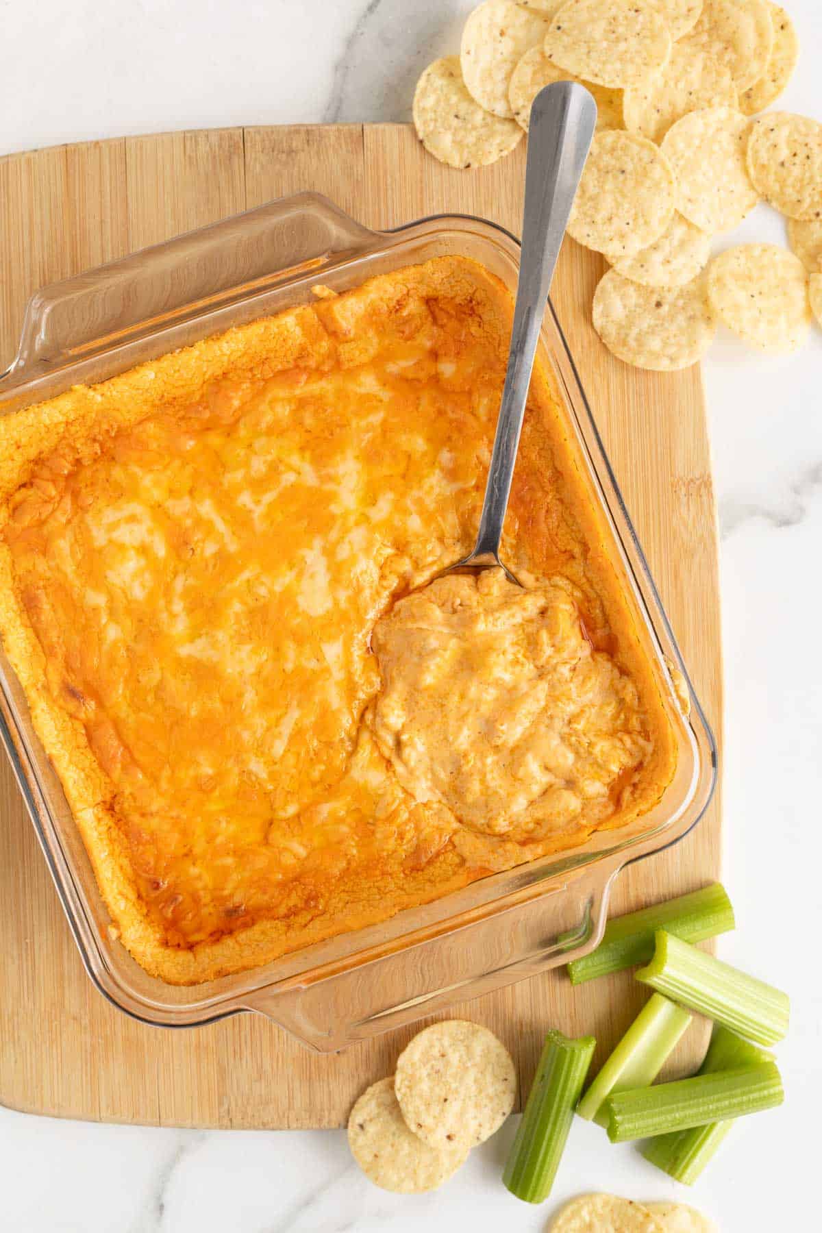  a large baking dish of Buffalo chicken dip recipe with a spoon ready to serve it